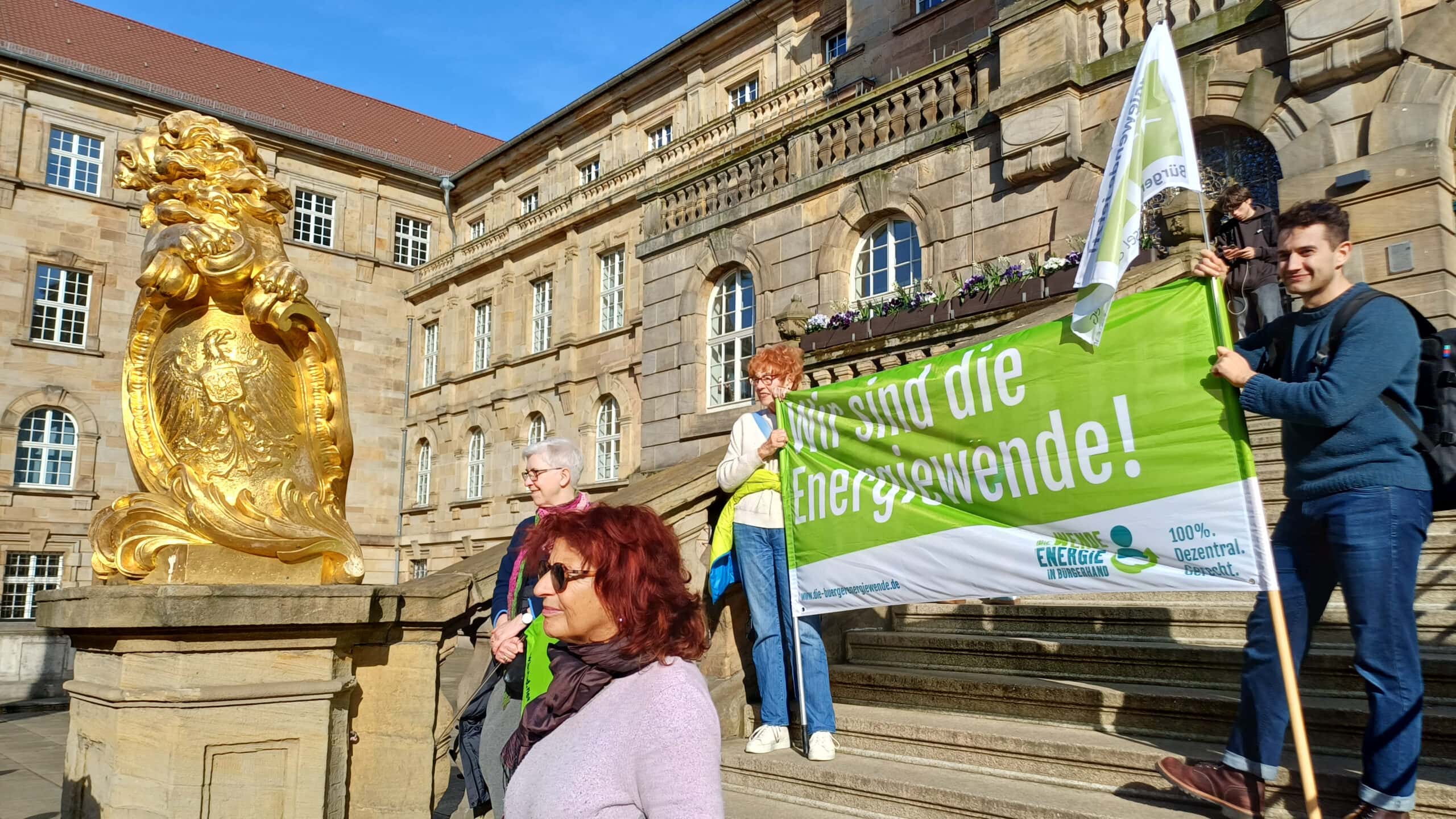 Demonstration für erneuerbare Energien vor Kasseler Rathaus mit Bürgerenergie-Flagge.