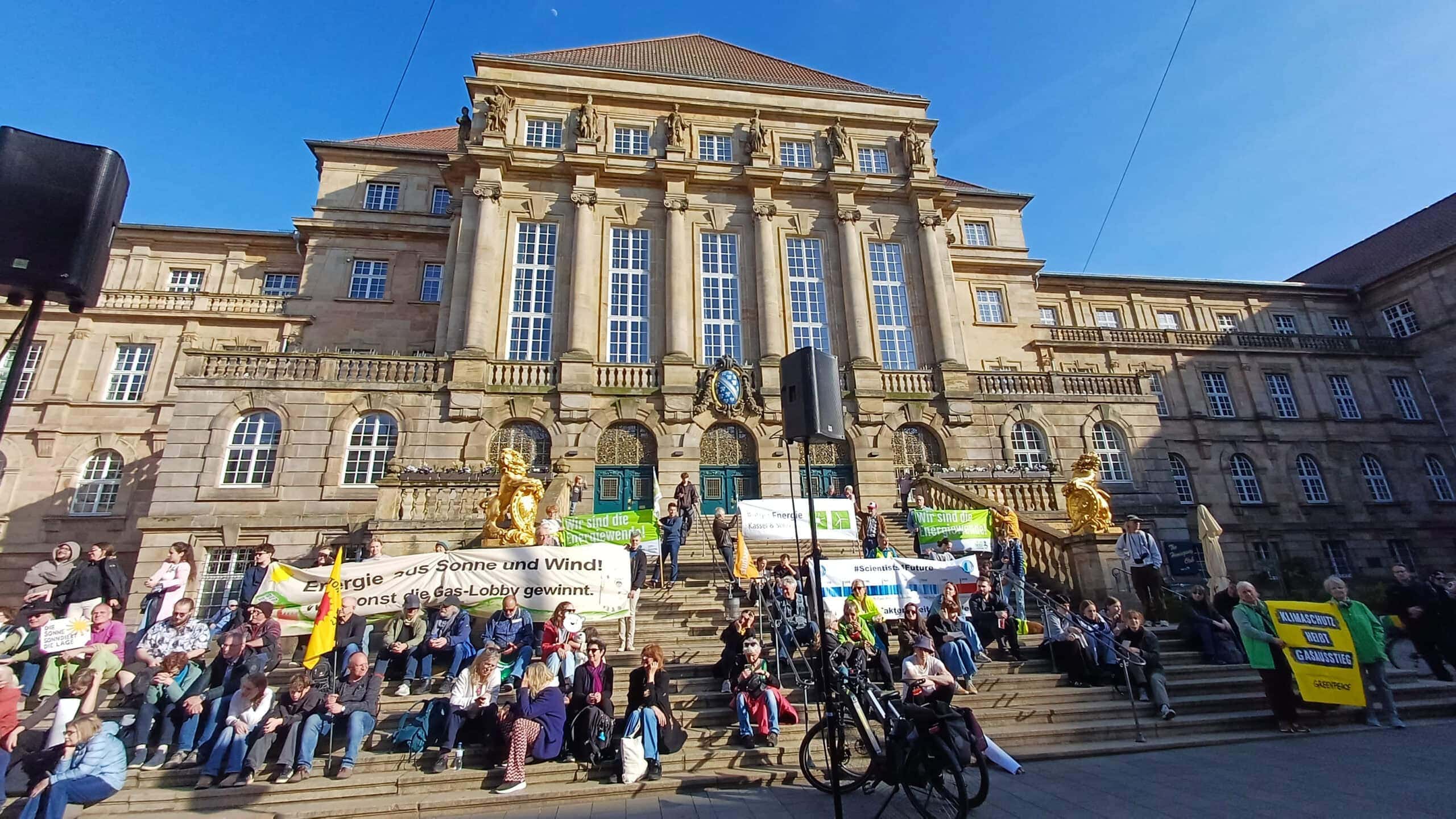 Menschen versammeln sich vor dem Kasseler Rathaus bei einer Demonstration.